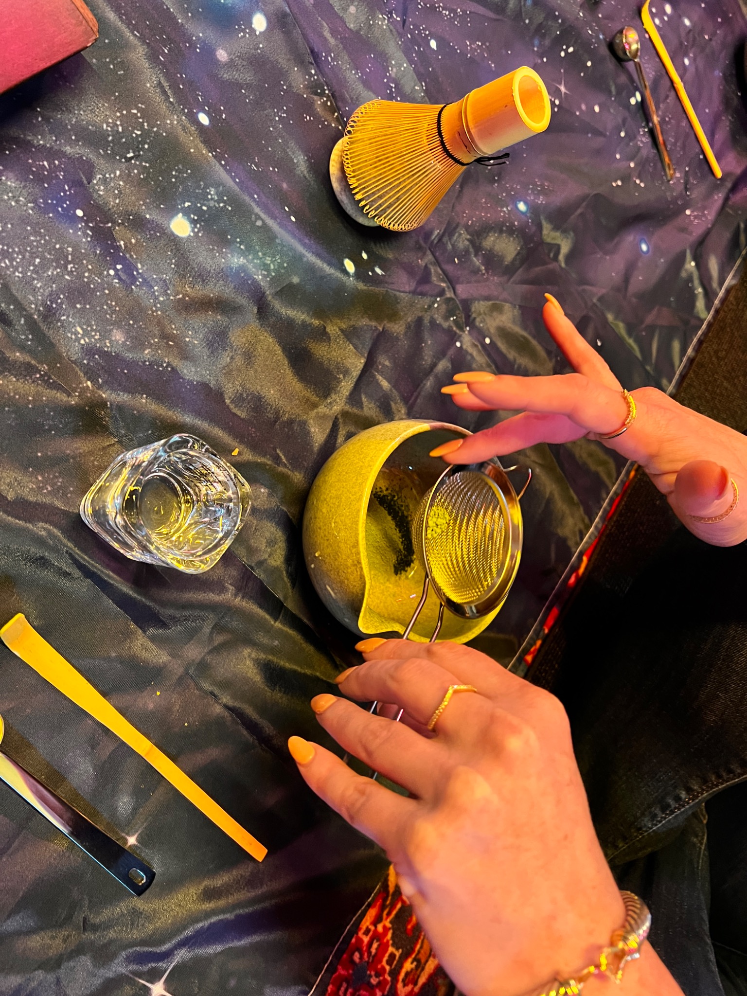 Hands working with wax, color, and tools on a protected table surface